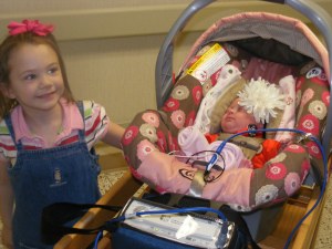 In her car seat ready to go home. Big bow on her head and heart monitor on her body.